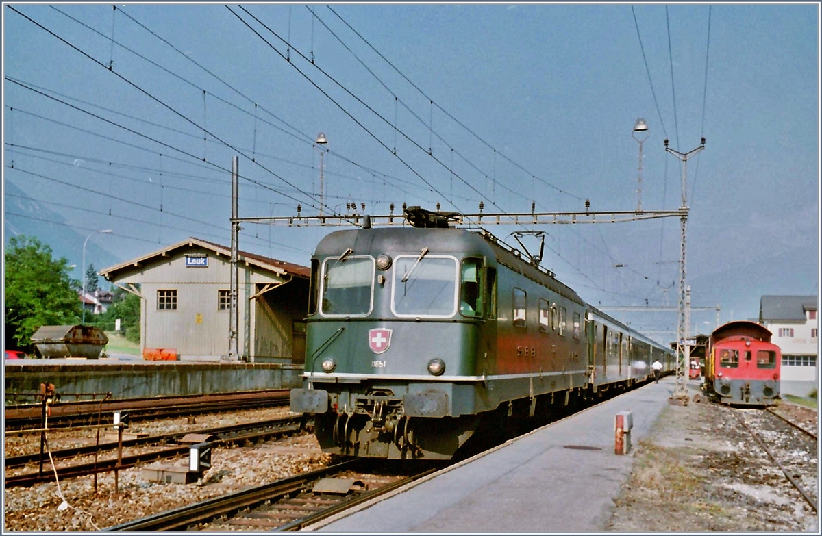 Der  alte  Bahnhof von Leuk lag gut hundert Meter südlicher als der neue und die Strecke Richtung Sion war bis Salgesch nur einspurig. Das Bild zeigt die Re 6/6 11651 mit einen IR Richtung Brig beim Halt im alten Bahnhof von Leuk. 

Im Juli 1995