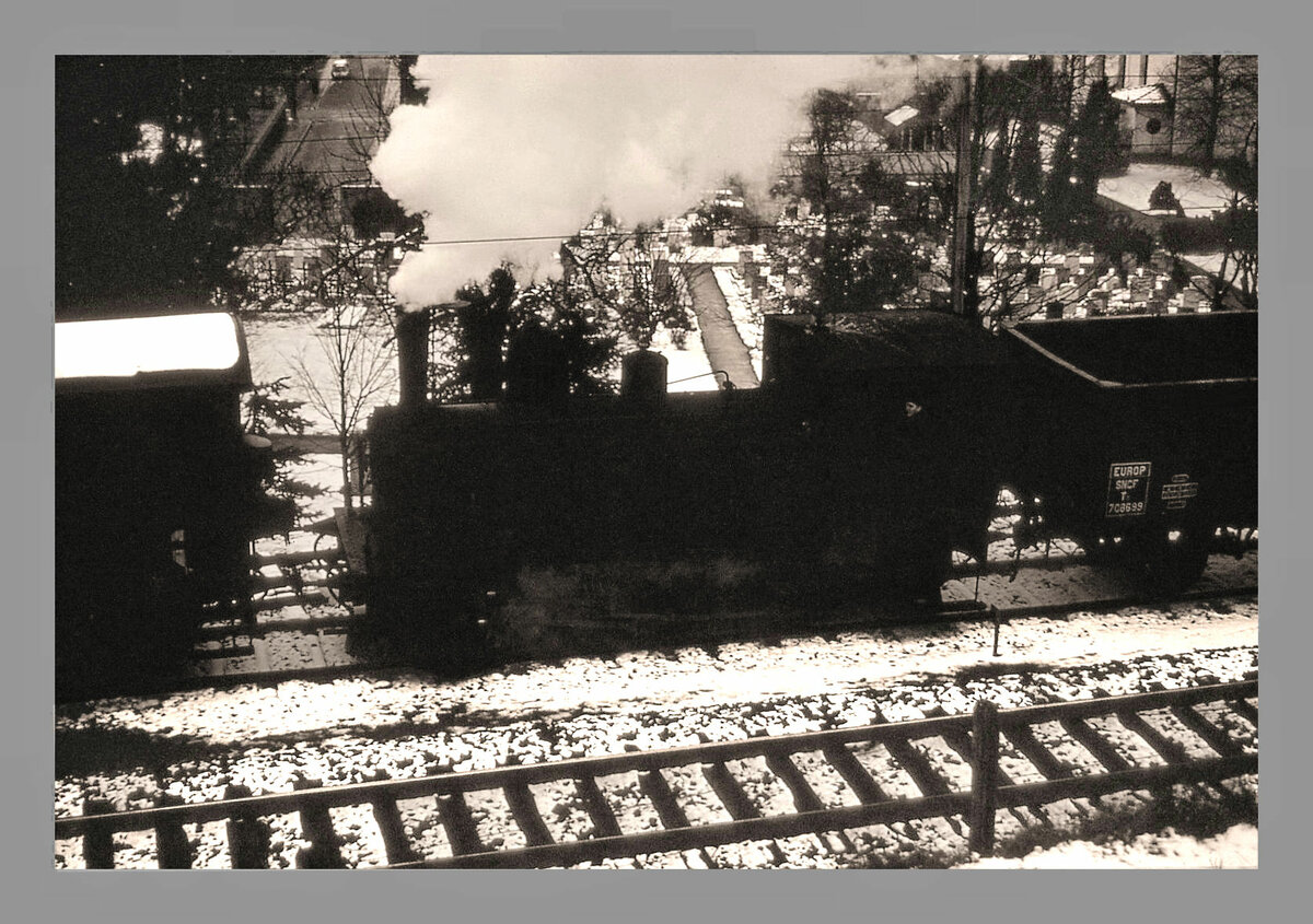 Die Gaswerkbahn Bern: Ich besass im Dezember 1964 nur eine kleine Kamera ohne Einstellungsm�glichkeiten. Das ergab in diesen tr�ben schneereichen Tagen leider keine guten Bilder. Dennoch seien einige Aufnahmen hochgeladen, die etwas von der damaligen Atmosph�re eines ganz normalen Dampfbetriebs mit allerlei Strecken- ebenso wie Rangieraufgaben wiederspiegeln. Hier rangiert die Gaswerk-Dampflok G�terwagen f�r die G�rbetalbahn (GBS, heute BLS); im Hintergrund der alte Friedhof von Wabern.  