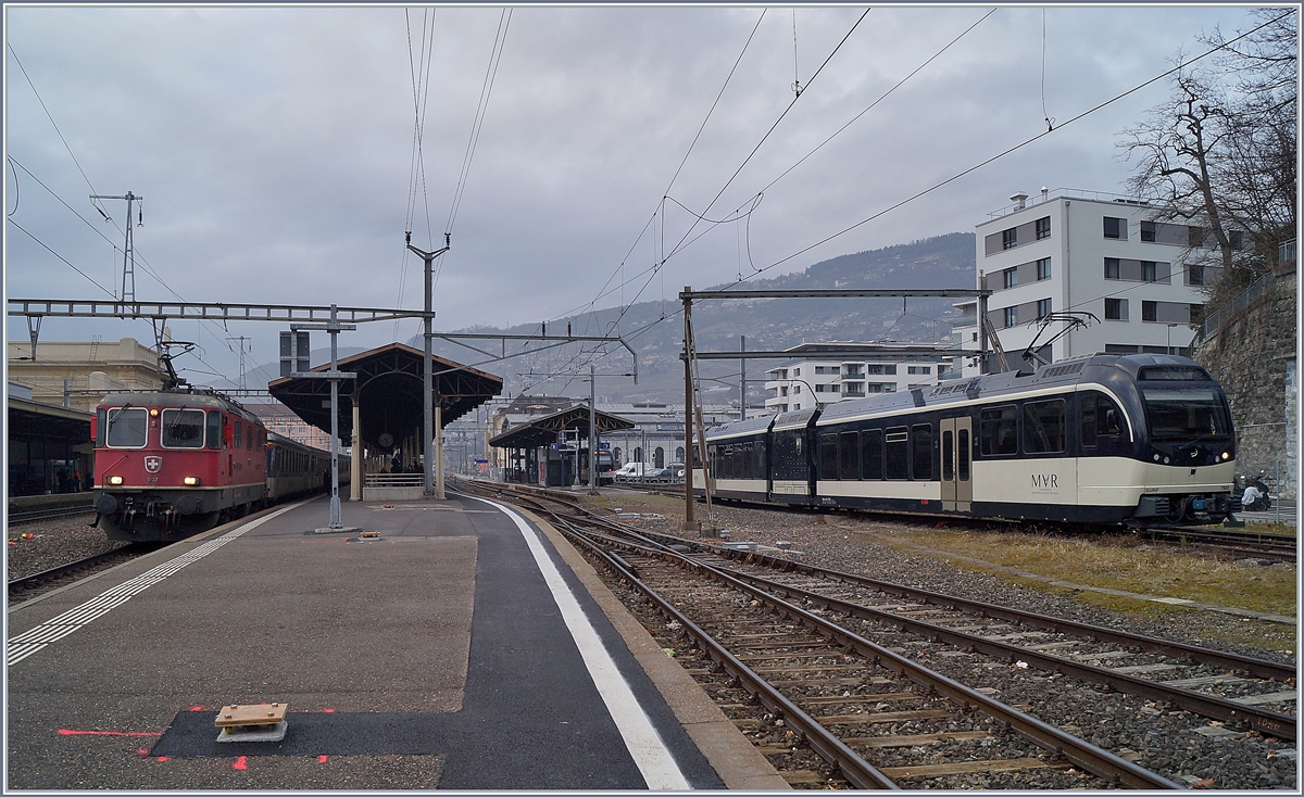 Die Re 4/4 II 11197 wartet in Vevey mit ihrem Dispozug (und der Re 4/4 II 11194 am Zugschluss) als IR90 1725 auf die Ausfahrt.
Rechts im Bild der CEV MVR ABeh 2/6 7503  Blonay-Chamby .

30. Januar 2020