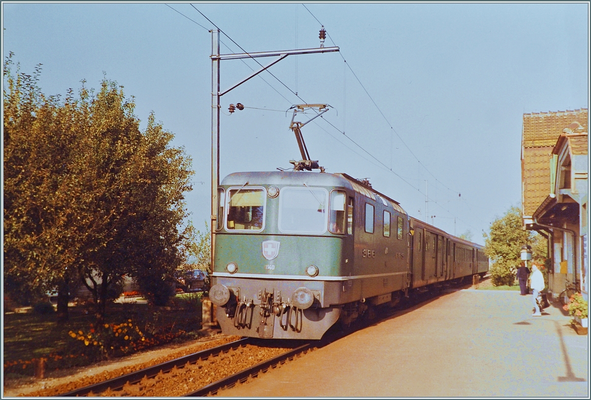 Die SBB Re 4/4 II 11140 erreicht den Halt Rüti bei Büren mit ihrem Regionalzug von Herzogenbuchsee nach Lyss.

Die Strecke von (damals) Neu Solothurn nach Busswil wurde am 4. Dezember 1876 eröffnet und am 3. Oktober 1944 elektrifiziert. 1994 wurde der Personenverkehr auf dem Abschnitt Solothurn - Büren an der Aare eingestellt, für das Tanklager  Thomen  verkehren weiterhin  Zustellfahren doch die Zeitweilig verkehrenden Dampfzüge von Solothurn nach Büren a/A mussten 2016 infolge einer maroden Brücke bei Büren eingestellt werden. 

Ein Analogbild vom Oktober 1984