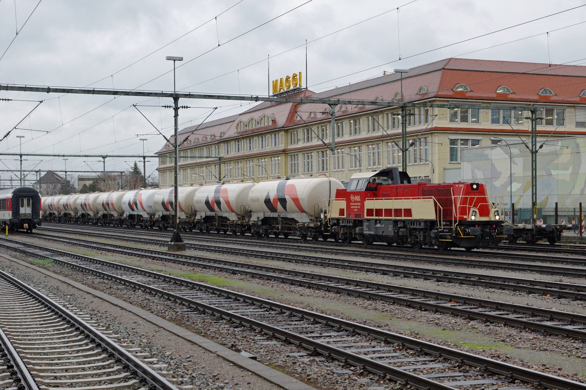 HZL: Fotografieren in Singen am 20. November 2015 trotz starkem Wind und Dauerregen. Die V 180 Gravita 15 L BB mit einem HOLCIM-BLOCKZUG in Singen vor der Kulisse der MAGGI FABRIK, dem Wahrzeichen des Bahnhofs Singen, kurz vor der Abfahrt nach ????
Foto: Walter Ruetsch 
