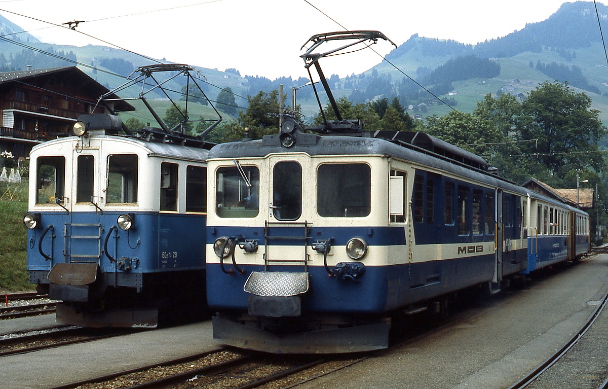 Im Juli 1983 begenen sich in Chateau d'Oex zwei Generationen: Der 1924 in Dienst gestellte BDe 4/4 28 vor einem G�terzug und einer der zwischen 1944 und 1946 gebauten BDe 4/4 3001-3006 mit einem Personenzug nach Montreux.