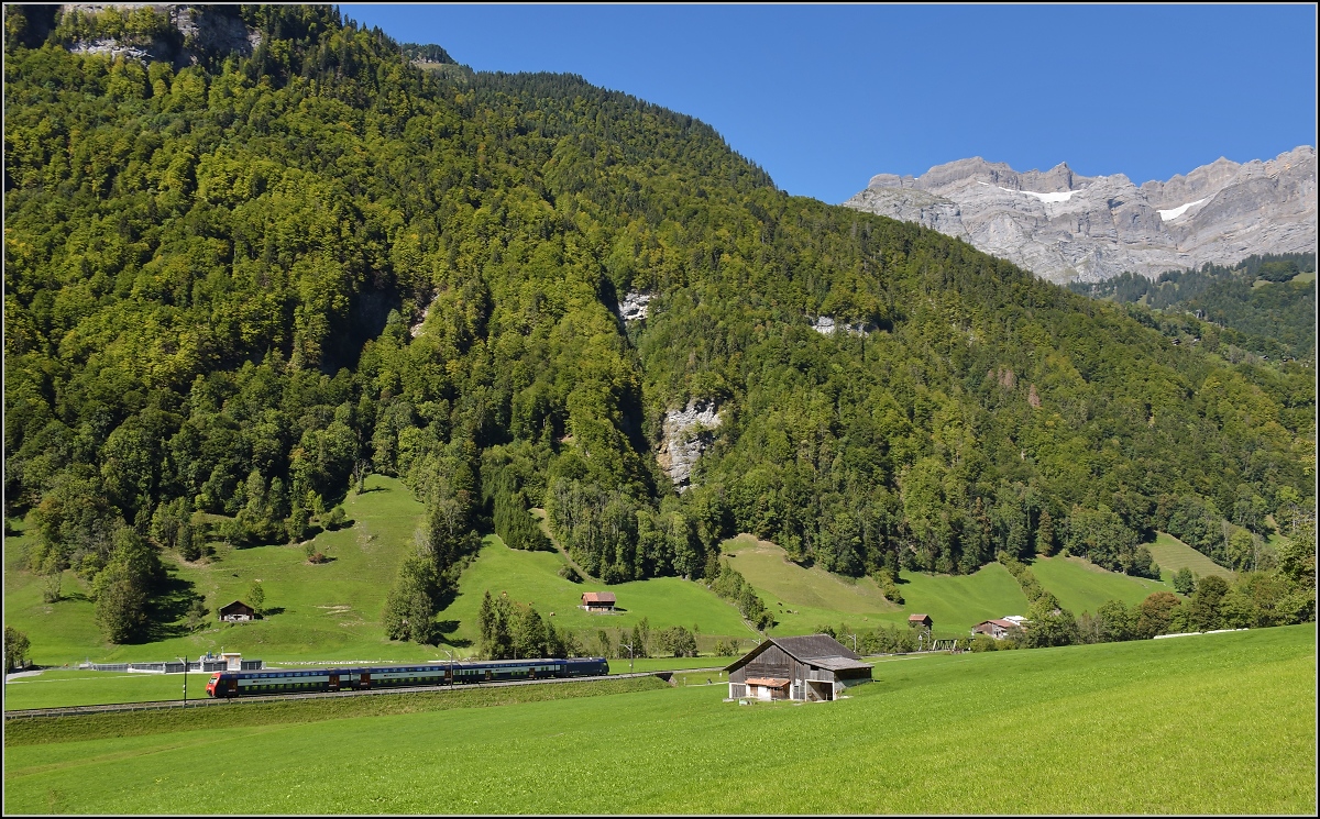 Im tiefeingeschnittenen Tal der Linth zeigt sich ein unbekannter Zug der S-Bahn Z�rich mit Re 450 in ganz besonderem Licht. Im Hintergrund erhebt sich das prominente Gl�rnisch-Massiv. Diesbach, September 2019.