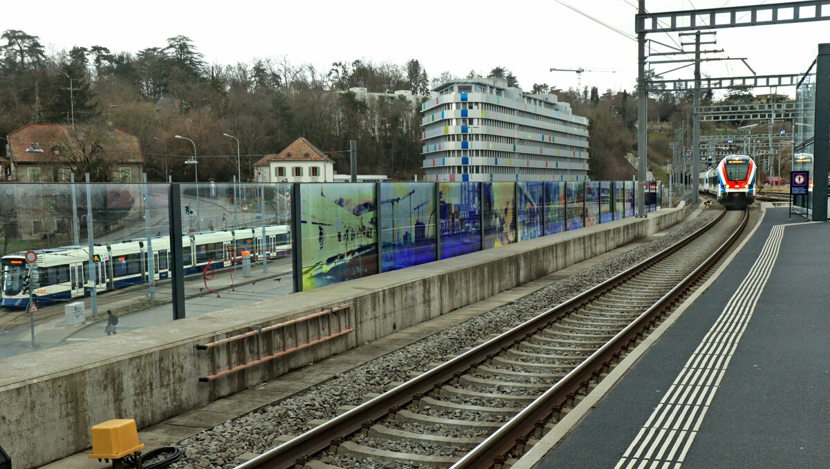 Lancy Pont Rouge, an der Strecke des Léman Express: Während ein SBB Flirt 522 228 nach Annemasse in Frankreich einfährt, wartet unten ein Tram der Linie 17 ebenfalls auf Abfahrt nach Annemasse. 10.März 2023 