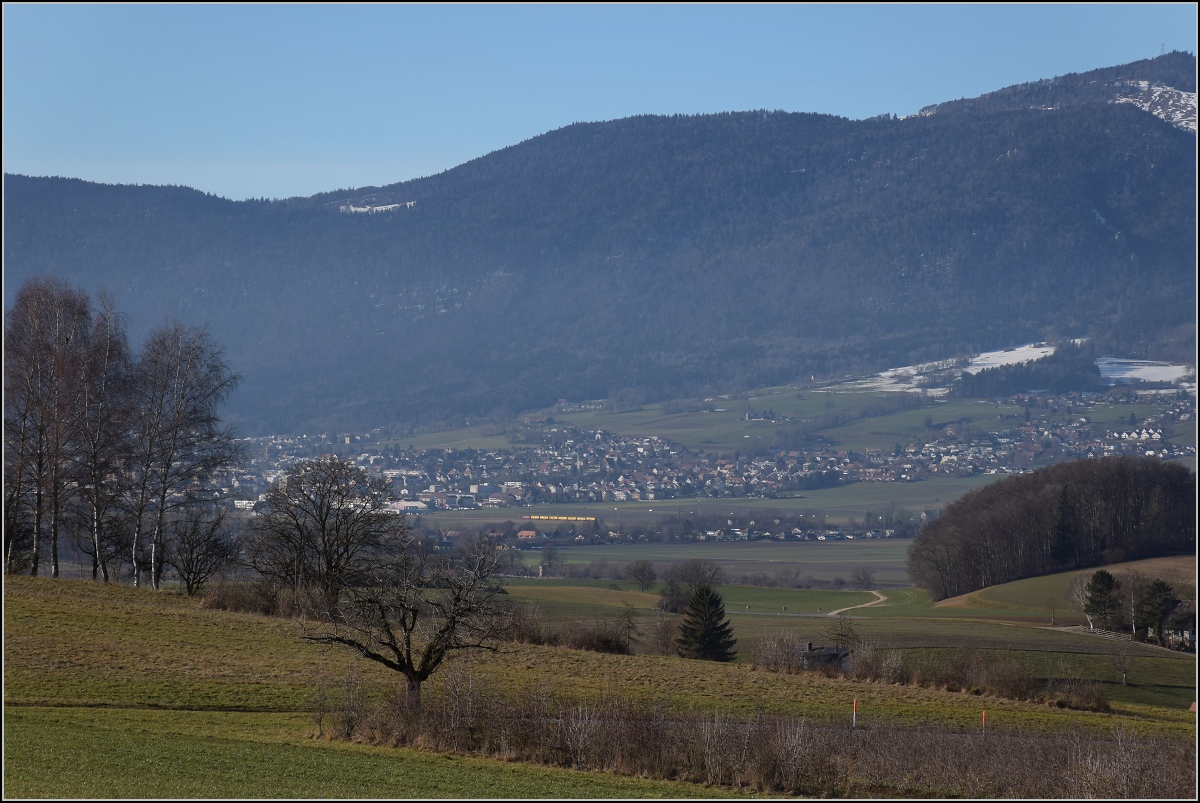 Viel Landschaft, wenig Zug am Jura.

Ein Postzug wird von einer Re 4/4 II auf der Juras�dfusslinie nach Bettlach gezogen. Januar 2022. 