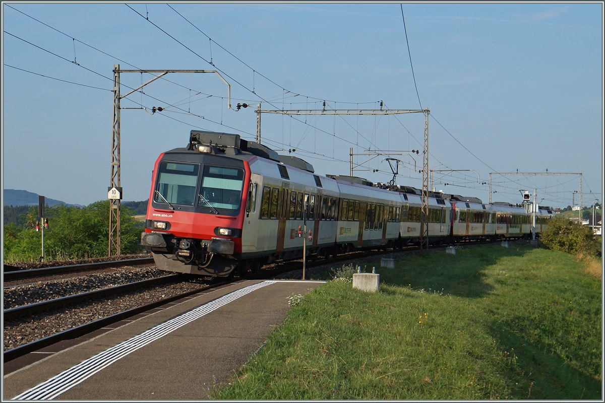 Zwei Domino Züge als RE Bulle/Palézieux - Bern auf dem Weg Richtung Fribourg erreichen noch unter der alten Fahrleitung den Halt Neyruz. 
6. Aug. 2015