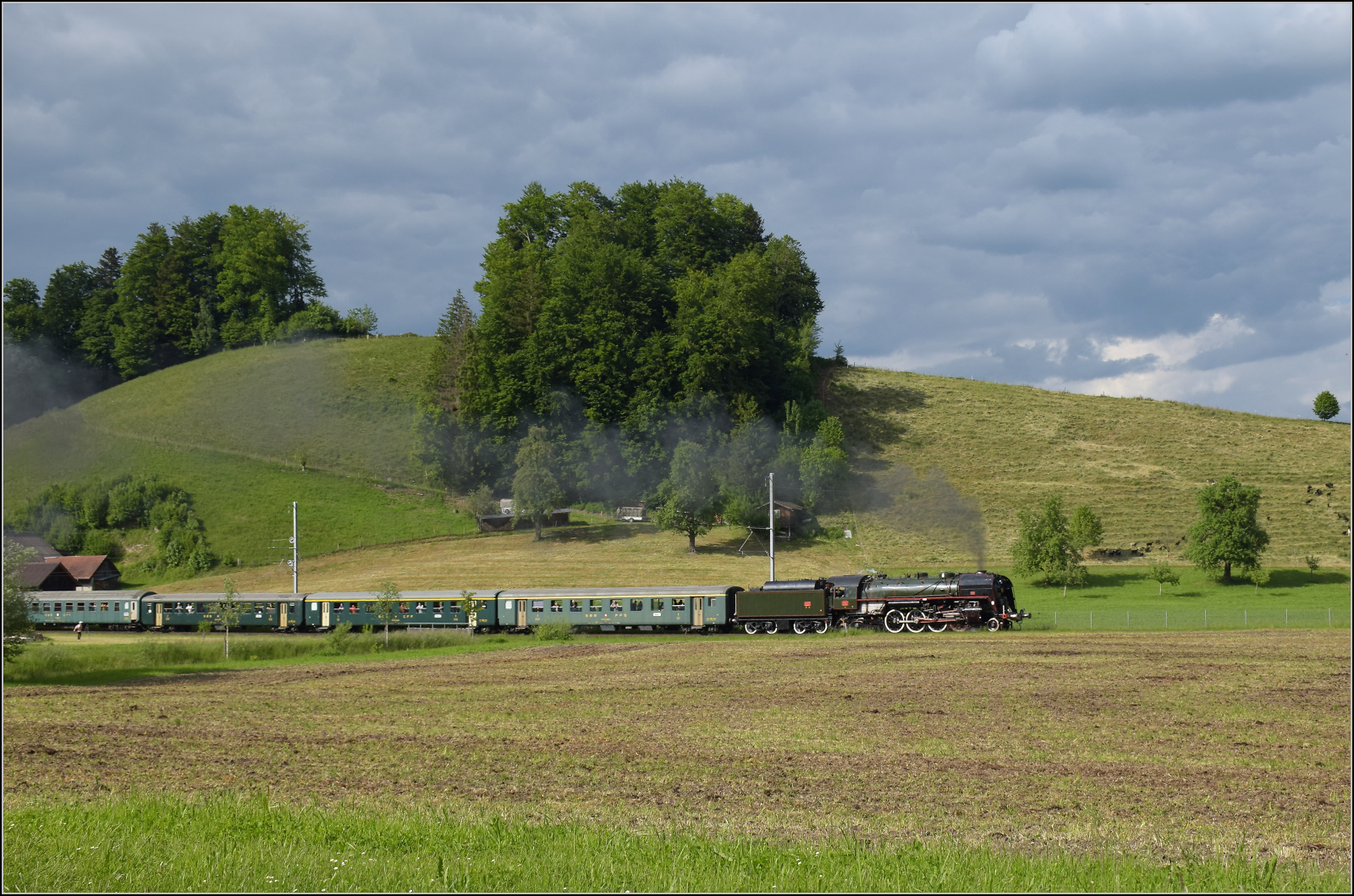 150 Jahre Emmentalbahn. 

141-R-1244 auf dem R�ckweg von der grossen Emmentalrundfahrt anl�sslich des Jubil�ums. Am Ortsausgang Menznau findet die Sonne ein Wolkenloch, freie Sicht auf die Strecke und die Strasse ist ohne Verkehr, so begann eine kurze Parallelfahrt, wie man sie nur selten durchf�hren kann. Mai 2025. 