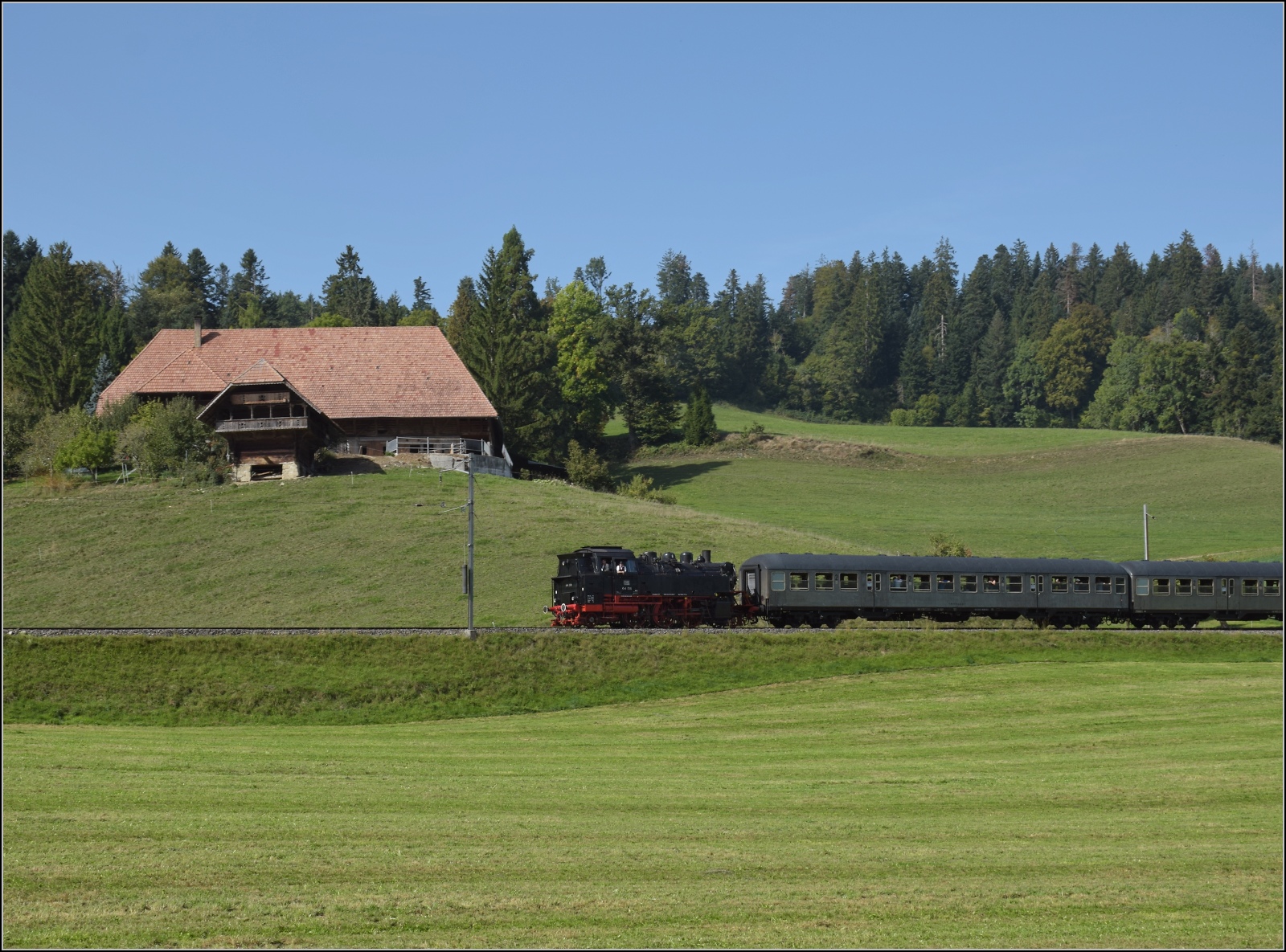 Dampftage Huttwil mit frisch genesenem Bubikopf. 

Bei Wydithub rollt der Zug mit 64 518 nach Sumiswald-Grünen hinunter. Oktober 2023.