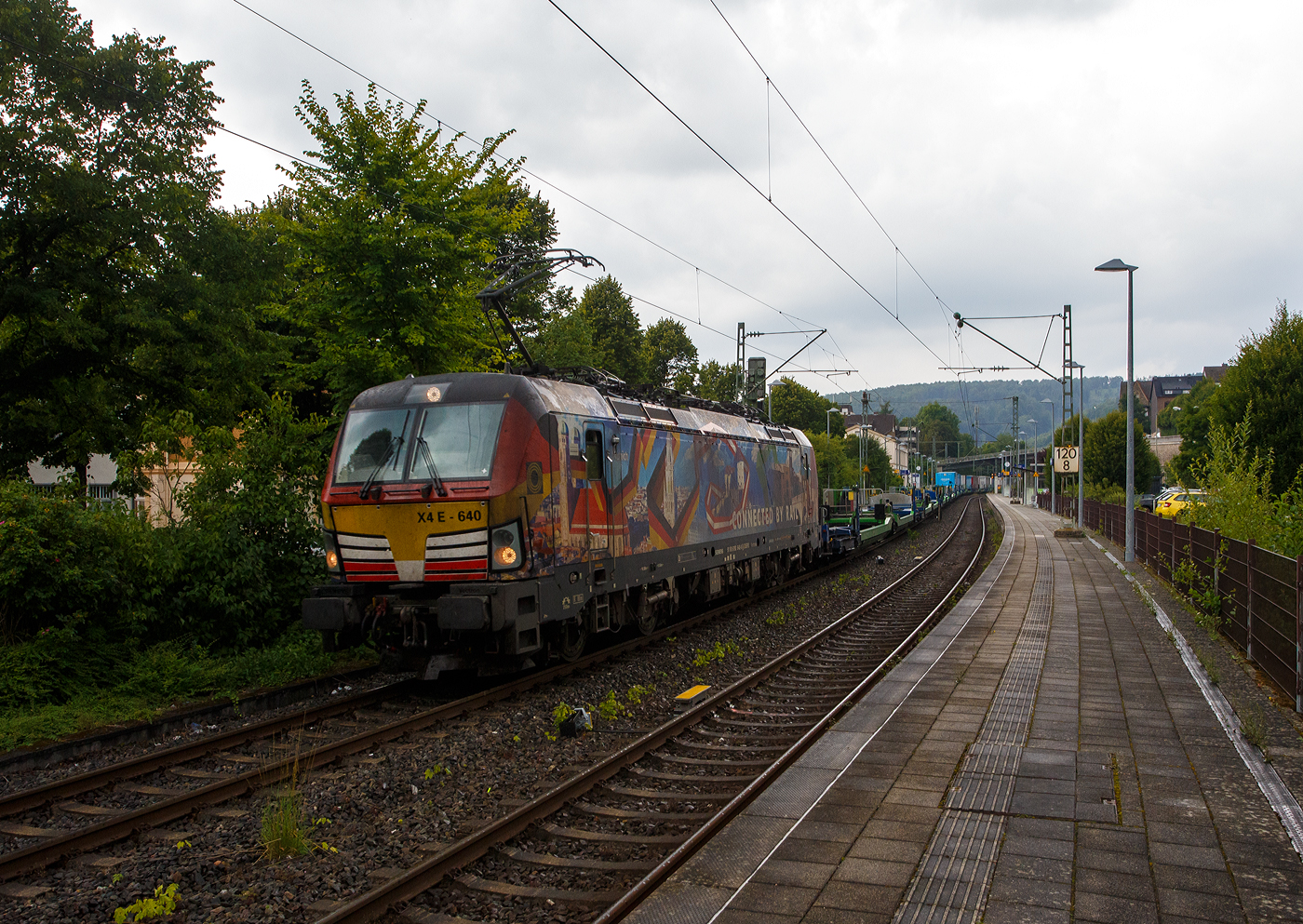 Die bunte, nun an die HELROM GmbH (Frankfurt am Main) vermietete Siemens Vectron MS X 4 E – 640 / 193 640-0 “Connected by Rail” (91 80 6193 640-0 D-DISPO) der Beacon Rail Capital Europe GmbH, München (BRCE / DISPO) fährt am 31 Juli 2025 bei leichtem Regen mit dem HELROM Trailer Zug Wien – Düsseldorf, einem besonderen KV-Zug, durch Kirchen/Sieg in Richtung Köln. 

Die Siemens Vectron MS - 6.4 MW wurde 2016 von Siemens in München-Allach unter der Fabriknummer 22164 gebaut. Im September 2016 wurde sie auf der Messe  InnoTrans 2016  in Berlin präsentiert. Danach wurde sie an die MRCE - Mitsui Rail Capital Europe GmbH (München) ausgeliefert. Sie war seitdem an die TX Logistik AG in Troisdorf vermietet, deren Werbekleid (Connected by Rail) aktuell auch noch trägt. Die TXL setzt nun aber auf eigene Loks (40 Siemens Vectron MS wurden bestellt), so wurde diese frei und ist z.Z. an die HELROM GmbH vermietet. 

Diese Vectron Lokomotive ist als MS – Lokomotive (Mehrsystemlok) mit 6.400 kW Leistung und 160 km/h Höchstgeschwindigkeit konzipiert. Sie ist in der Variante A09 ausgeführt und hat so die Zulassungen für Deutschland, Österreich und Italien (D / A / I), daher trägt sie auch die Werbung München, Kufstein, Verona (Connected by Rail). 

Die Lok wurde an die MRCE - Mitsui Rail Capital Europe GmbH in München ausgeliefert, seit September 2023 hat die Beacon Rail Metro Finance B.V. die Mitsui Rail Capital Europe B.V. (Amsterdam) und somit auch die Mitsui Rail Capital Europe GmbH im München übernommen, so firmiert sie nun als Beacon Rail Capital Europe GmbH, München (BRCE / DISPO).