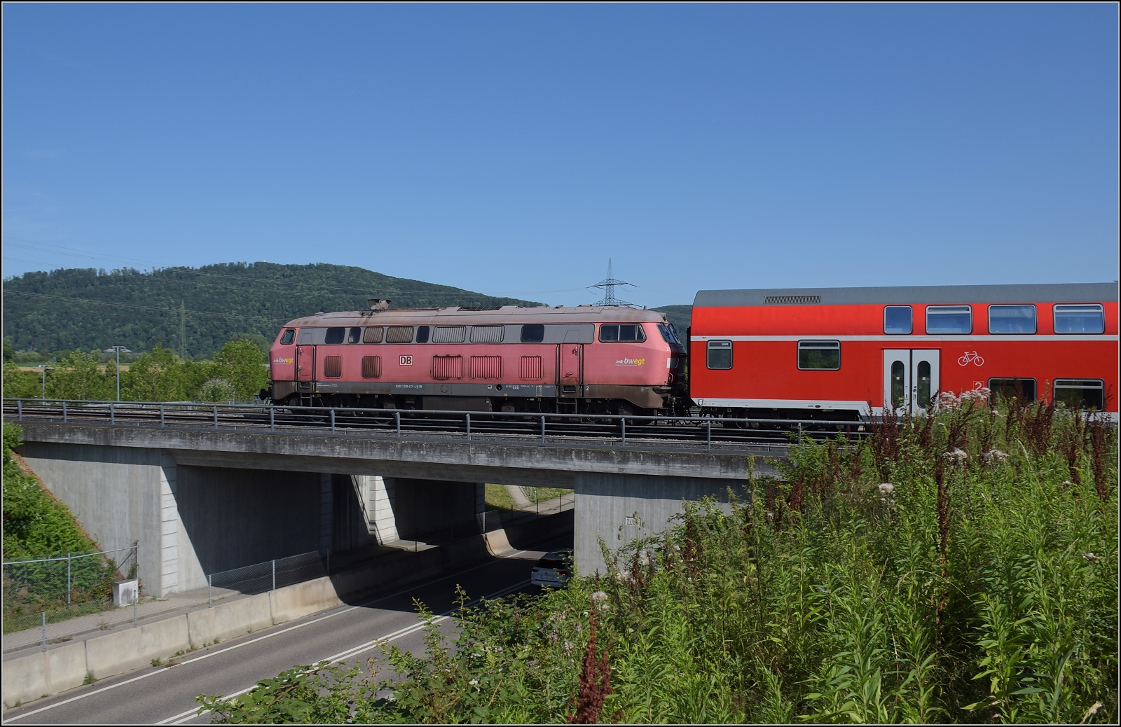 Nur f�r kurze Zeit: Fast historischer Grossdiesel an zwei Stellen in der Schweiz. Aus Basel bad Bf brummt 218 417 vorbei mit Ziel Friedrichshafen. Ihr Motor ist weithin h�rbar, aber direkt neben der Strecke ist sie eine dahingleitende Fl�sterlok. Hingegen das Rumpelstilzchen alias Heulsuse alias BR 245 hat zwar leise Dieselmotoren, benimmt sich ansonsten aber eher wie eine Gleisstopfmaschine... Warmbach, Juli 2023.