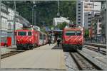 Zwei MGB HGe 4/4 warten in Brig mit einem Glacier-Express und Regionalzug Richtung Zermatt auf die Abfahrt.